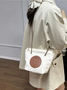 Sac seau fourre-tout beige minimaliste avec bandoulière chaîne et écusson pour femme