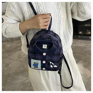 Detail of navy blue plaid backpack with unique shirt collar design and bear patch
