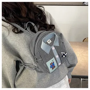 Detailed view of mini striped backpack with shirt collar, bow, and bear patch detail