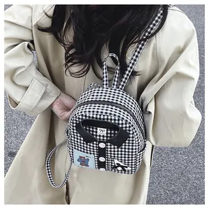 Detail of plaid backpack featuring cute bear patch and mini collar design on canvas