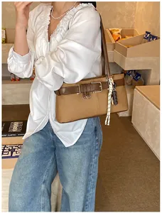 Retro camel Boston bag with brown leather strap and woven charm shown in a cozy cafe