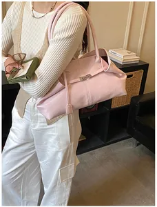Detail of pink lychee grain leather tote bag with silver metal buckle on model shoulder