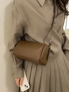 Brown textured leather baguette bag with strap worn on beige minimalist outfit