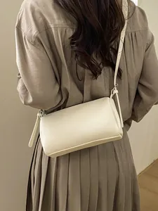 Creamy white cylinder bag with lychee texture leather and silver hardware on model