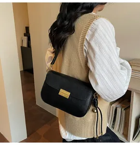 Detail of a vintage black leather box bag with gold metal lock on a female model