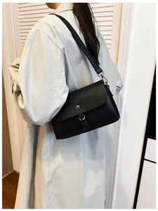 Close-up of black lychee grain leather crossbody bag with silver hardware on a model