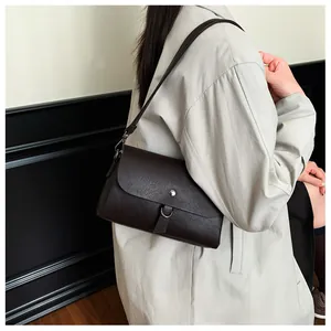 Detail of dark brown leather square bag with metallic D-ring buckle on trench coat