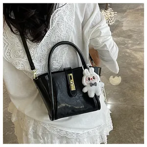 Détail du sac seau noir en cuir verni avec boucle dorée et breloque lapin en peluche