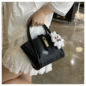 Détail du sac seau noir brillant avec boucle dorée et pendentif lapin blanc mignon