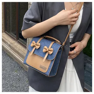 Détail du sac cabas en denim et cuir kaki avec nœuds décoratifs et bandoulière réglable