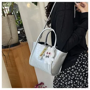 Détail du sac seau argenté texturé avec fermoir doré et breloque lapin en peluche mignonne