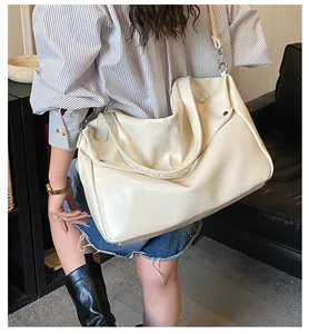 Detail einer cremeweißen glänzenden Leder-Tote-Bag an der Schulter des Models