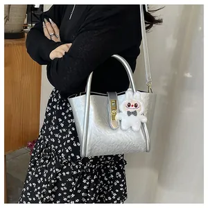 Détail du sac argenté avec fermoir rotatif doré et pendentif lapin en peluche doux