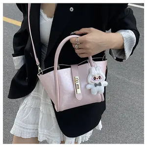 Gros plan du sac seau rose clair avec fermoir rotatif argenté et breloque lapin