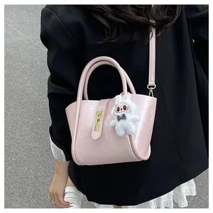 Détail du sac seau rose avec boucles dorées et pendentif lapin en peluche blanc sur modèle