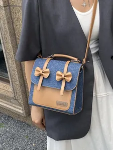 Sac cabas rétro en denim avec nœuds en cuir, porté en bandoulière par le mannequin