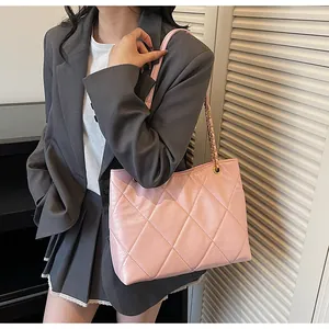 Macro view of pink quilted tote bag with metallic chain strap and glossy leather finish