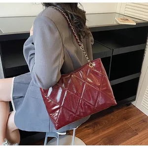 Detail of burgundy quilted leather shoulder bag with gold chain strap worn by a model