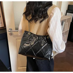Close-up of black quilted chain tote bag worn by a model in a stylish indoor setting