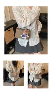 Detalle del bolso bandolera caqui con un colgante de osito y cremallera metálica resistente