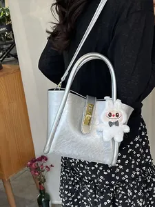 Sac seau argenté avec breloque lapin porté par un mannequin en robe fleurie