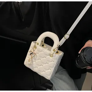 Détail du sac à main matelassé blanc avec clous dorés et breloque papillon en perle
