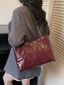 Burgundy quilted leather tote bag with gold chain strap carried by fashion model