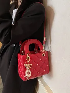 Petit sac carré rouge matelassé avec étoiles dorées et breloque perle porté par mannequin