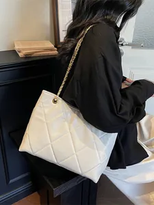 White quilted leather tote bag with gold chain strap shown on model for elegant daily use