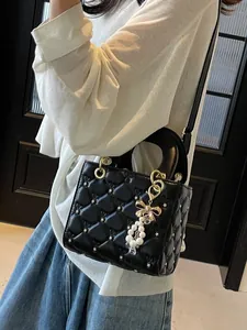 Sac bandoulière matelassé noir avec clous étoiles en métal et pompon nœud perlé