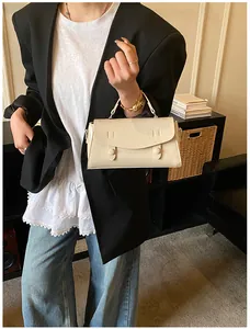 Chic off-white baguette bag with dual decorative straps styled with a casual blazer