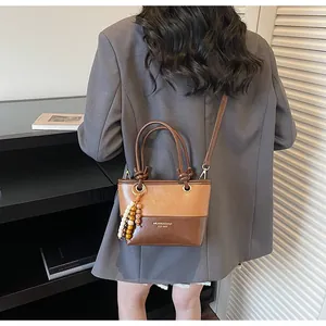 Dettaglio della borsa a secchiello vintage con pelle a contrasto e ciondolo di legno
