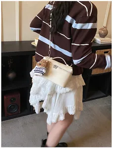 Detalle de bolso caja en cuero beige con correa bandolera y un lindo adorno de oso