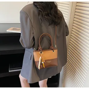 Dettaglio di una mini borsa a secchiello in pelle bicolore con ciondolo decorativo