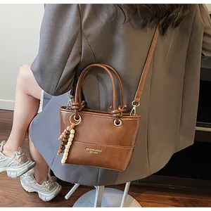 Dettaglio della borsa a secchiello marrone vintage con ciondolo in legno e logo stampato