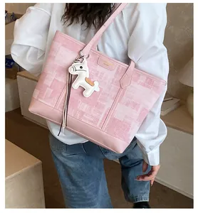Dettaglio borsa tote rosa con texture in tessuto, placca dorata e ciondolo a cavallo