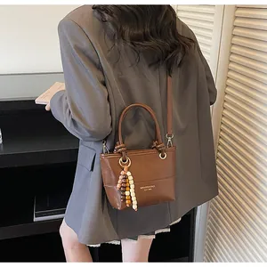 Dettaglio borsa a secchiello vintage marrone con nappa di perline e dettagli in metallo