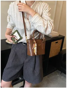 Brown retro bucket bag with beaded charm accessory shown in a lifestyle daily setting