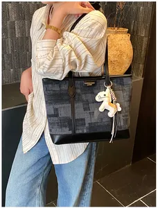 Dettaglio della borsa tote con trama astratta, finiture in pelle e ciondolo a pony