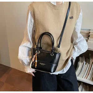 Borsa a secchiello in pelle nera con scritta dorata e ciondolo di perle indossata