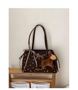 Detail of a brown tote bag featuring star patterns, puppy embroidery, and a plush charm