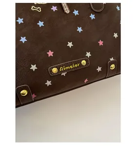 Macro shot of dark brown star print tote bag featuring a gold Aimair metal plaque
