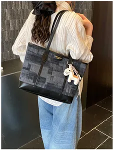 Dettaglio borsa shopper grigio scuro con fondo in pelle nera e ciondolo a pony