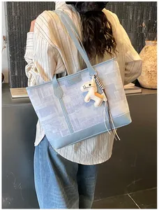 Dettaglio borsa tote azzurra testurizzata con logo dorato e charm a forma di cavallo
