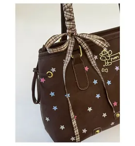Close-up of brown tote bag with colorful stars and checkered ribbon bow on the handle