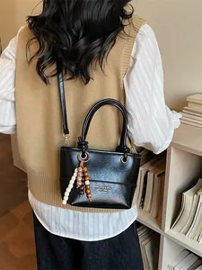 Borsa a secchiello retrò in ecopelle nera con ciondolo di perline in un interno accogliente