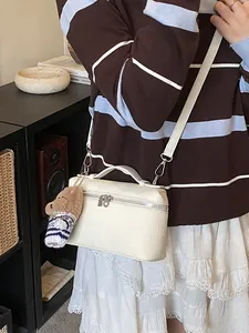 Bolso bandolera minimalista de cuero beige con un adorable colgante de oso pardo