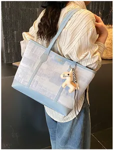 Dettaglio della borsa tote azzurra con trama e ciondolo a forma di cavallo su modella