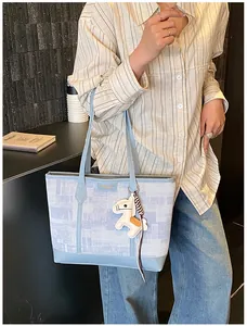 Dettaglio di borsa tote azzurra con ciondolo a cavallo sulla tracolla in un interno