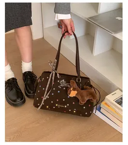 Detail of brown suede tote with star embroidery and plush dog charm on handle